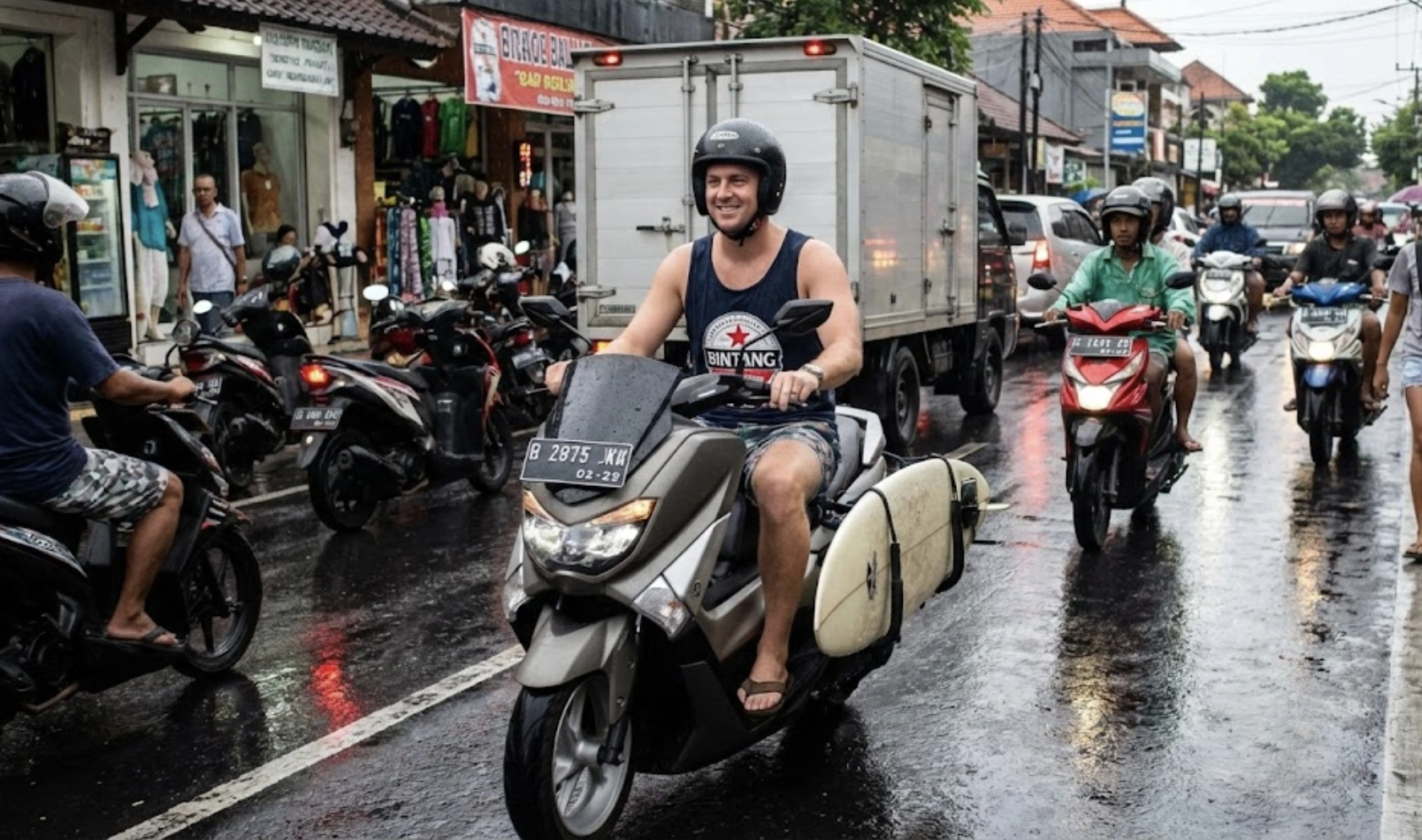 A tourist riding a NMAX scooter in Bali traffic wearing a helmet.